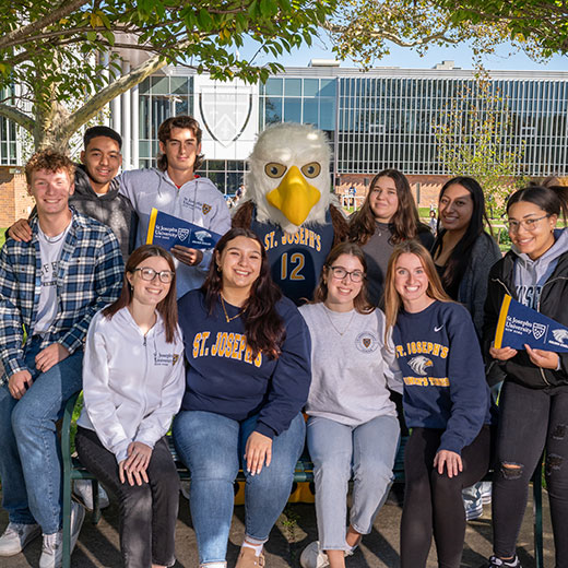 A group of students smiling with the school mascot. Links to Gifts by Will