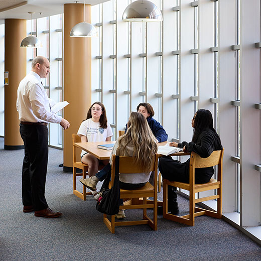 A professor talking to a group of students.